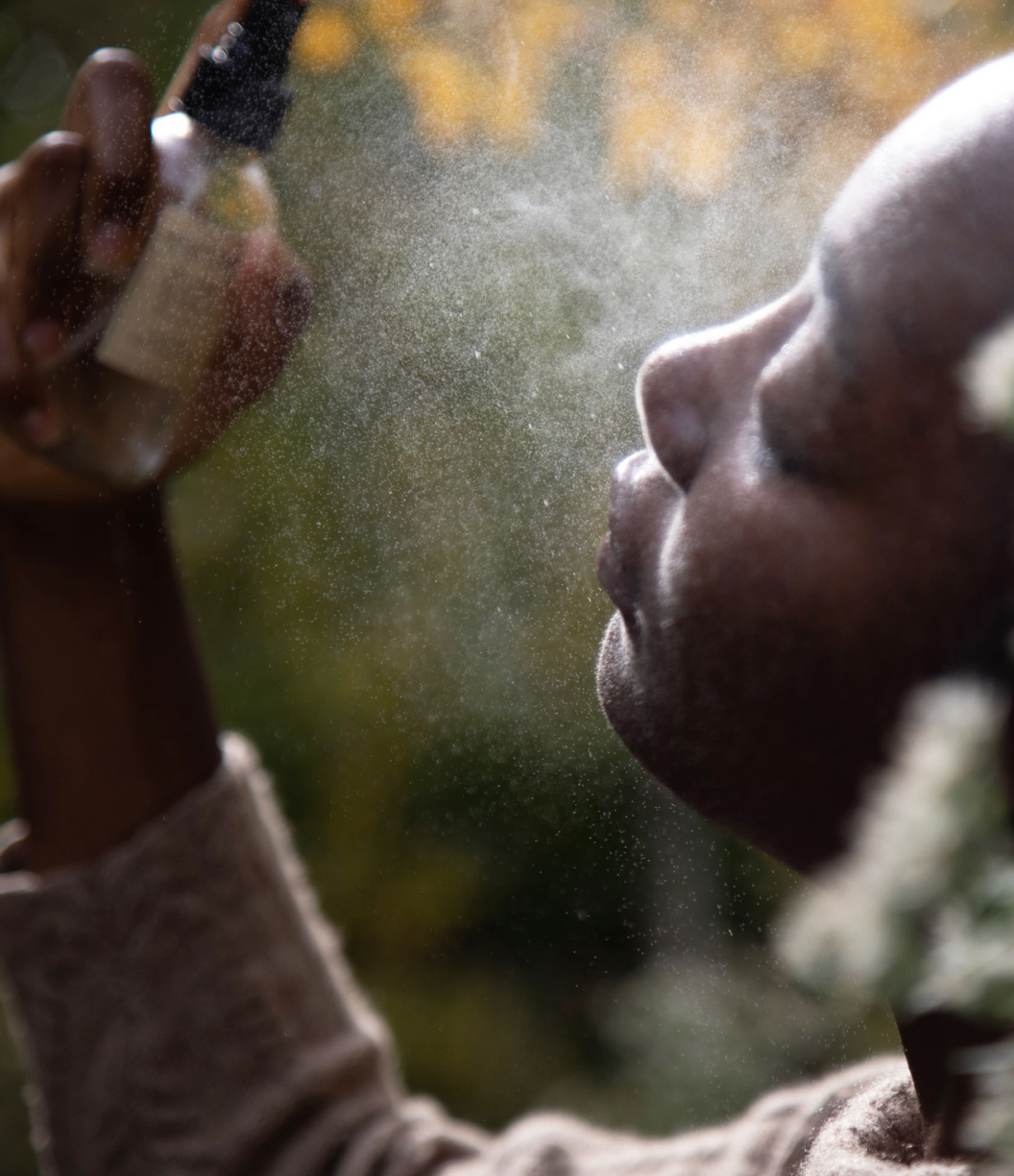 Person holding a spray bottle with water droplets in the foreground