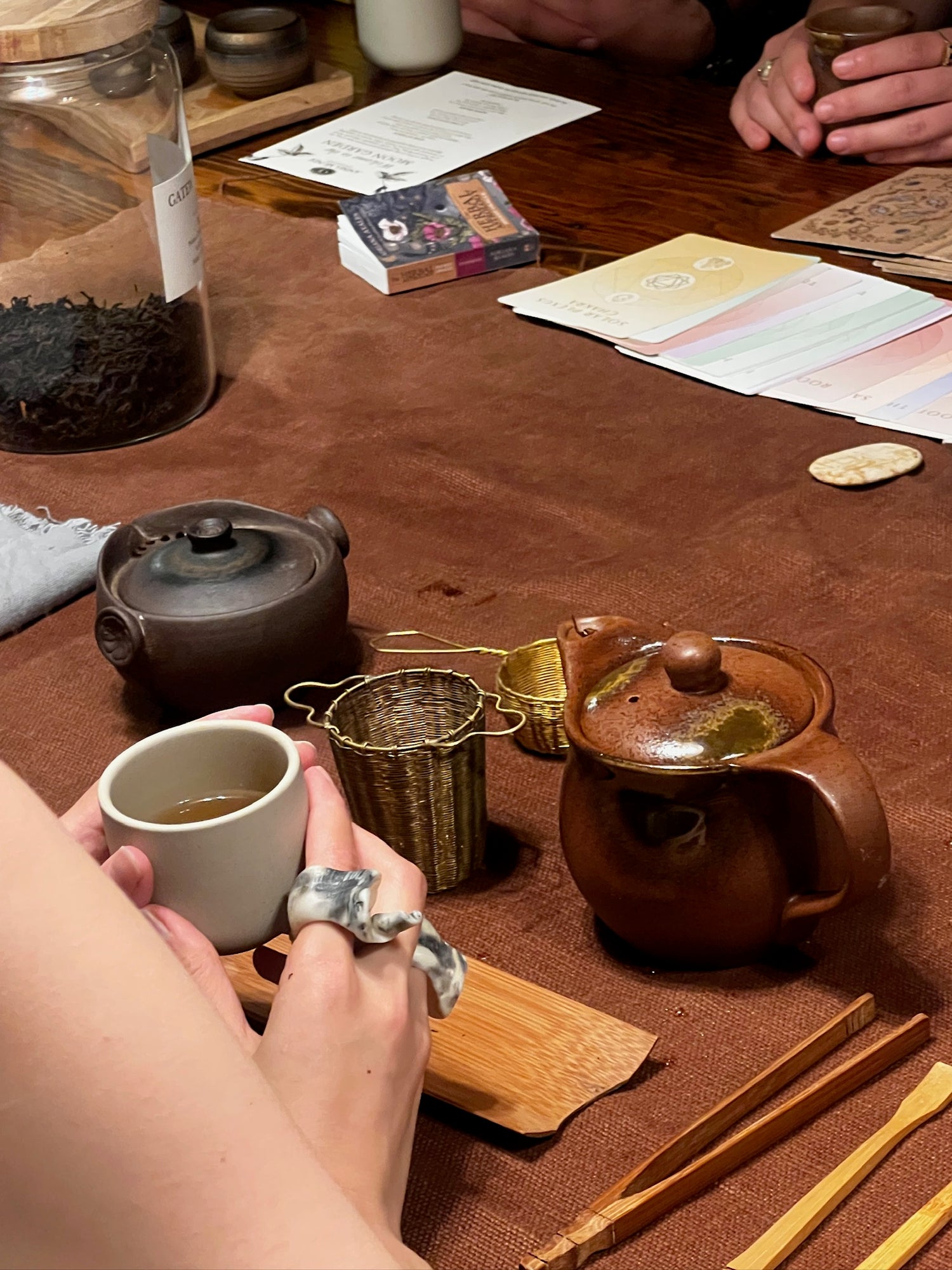 Tea-making setup with teapot, cups, and tea leaves on a wooden table.
