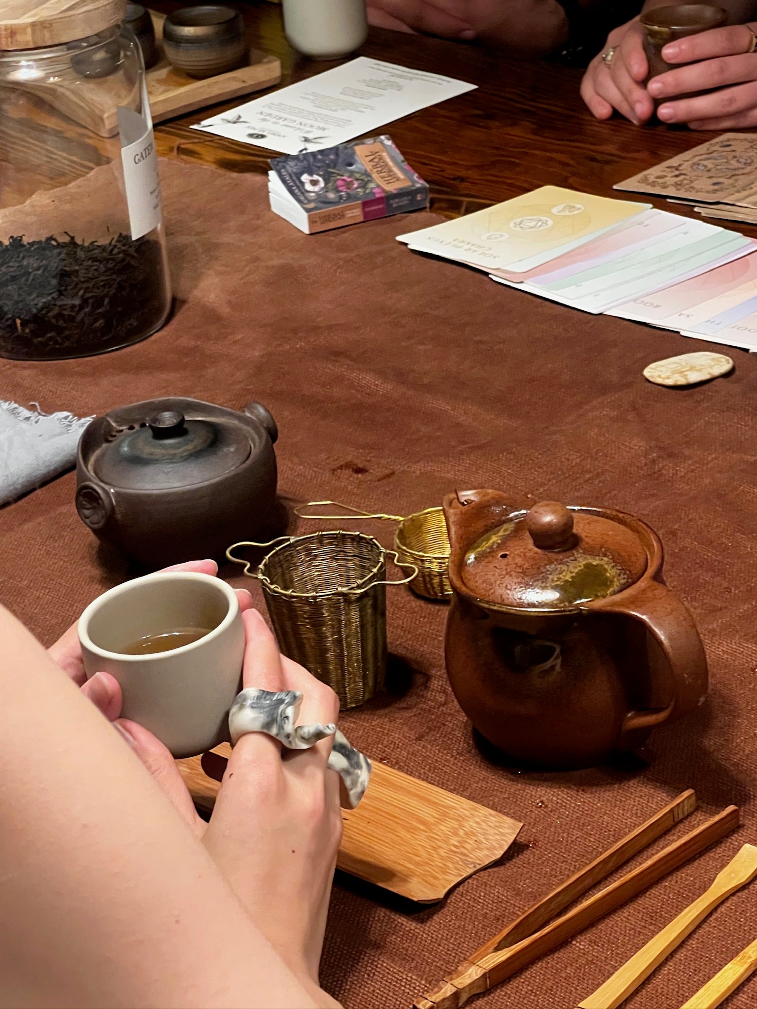 Tea-making setup with teapot, cups, and tea leaves on a wooden table.