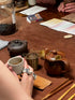 Tea-making setup with teapot, cups, and tea leaves on a wooden table.