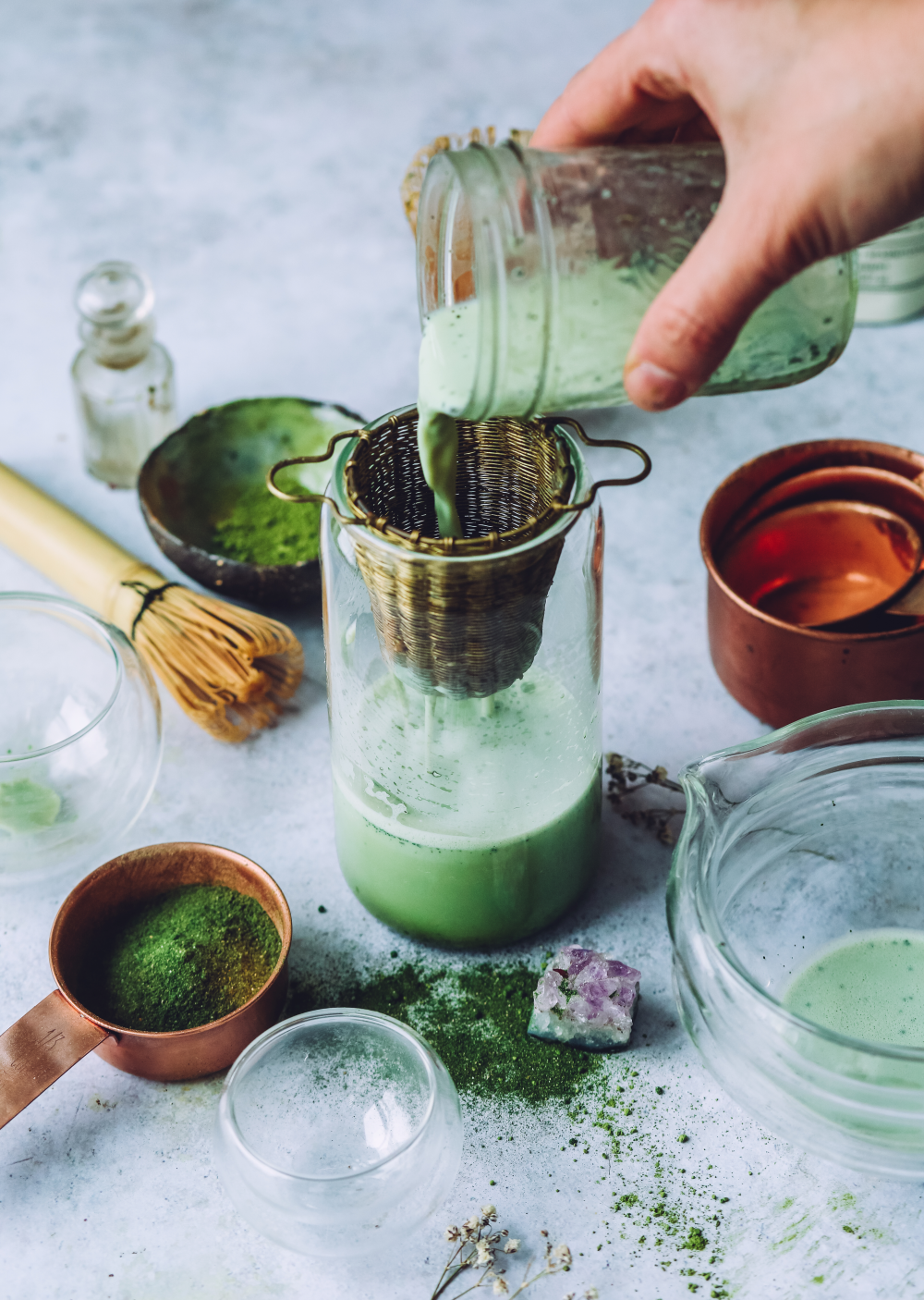 image of the liver vitality product being poured into a glass jar set on a background of botannical products from anima mundi